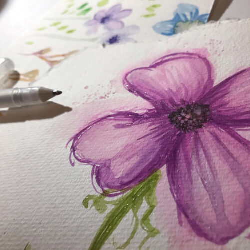 Close-up of a purple flower being painted with watercolors, showing brushes and painting process